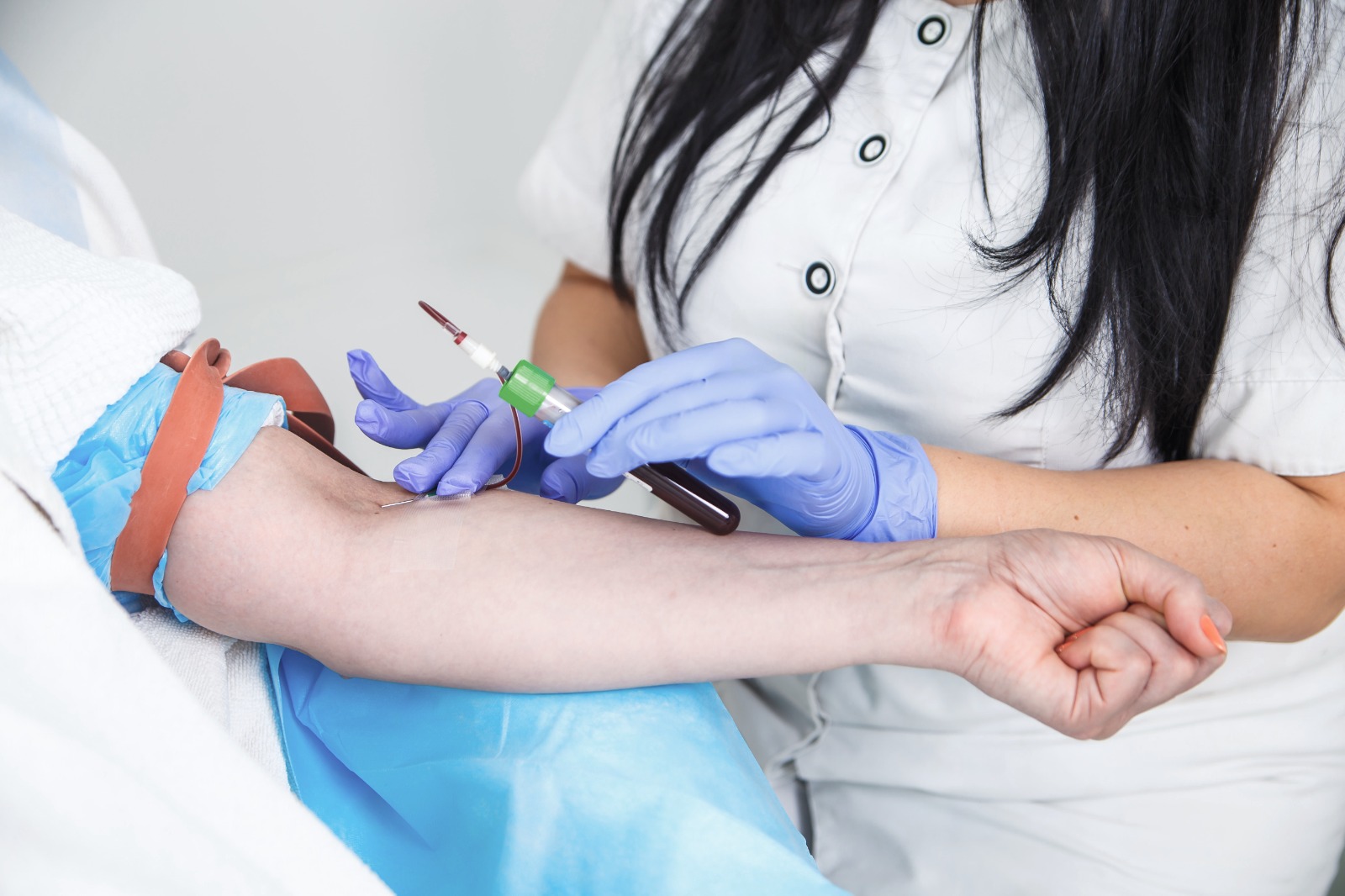 Nurse taking blood sample from arm of the patient